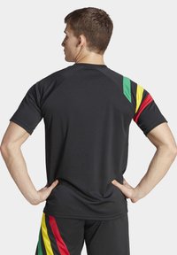 Zwart sportshirt met korte mouwen, voorzien van diagonale strepen in rood, geel en groen op de linkerschouder. Soepele textuur, aansluitend ontwerp.