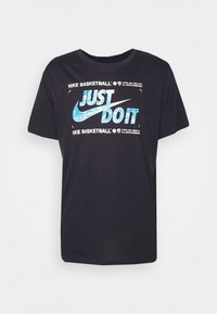 Camiseta negra de algodón, con un gráfico azul de "JUST DO IT" y el logo de Nike, de mangas cortas y diseño de cuello redondo.