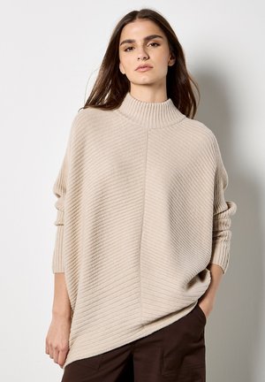 Maglione beige a collo alto a coste, con una vestibilità rilassata e spalle scese, caratterizzato da un motivo testurizzato e fessure ai lati in fondo.