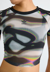 Black and white cropped mesh top with a colorful abstract pattern, featuring an Adidas logo on the chest and a ribbed neckline.