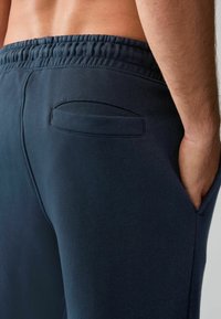 Navyblaue Sweatpants mit weichem Material, elastischem Bund und einer einzigen Gesäßtasche mit abgerundetem Eingriff.
