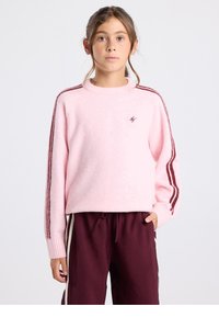 Hellrosa, flauschiger Pullover mit gerippten Bündchen und rundem Halsausschnitt. Verziert mit dunkelroten Streifen entlang der Ärmel und einem kleinen Logo auf der Brust.