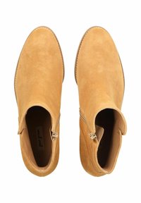 Botines de ante en color camel con acabado suave. Cuentan con cierre lateral, punta redondeada y detalles de costuras sutiles. Tacón plano.