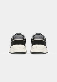 Black athletic shoes with a smooth texture, featuring a white sole, grey accents on the heel, and embossed Champion logo on the back.