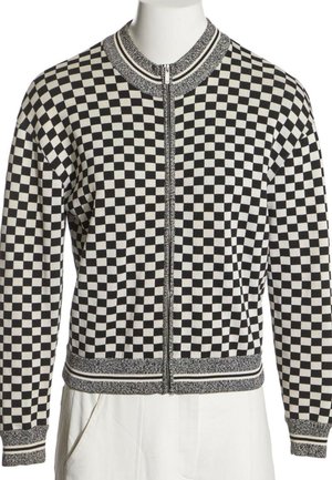 Veste zippée à carreaux noir et blanc avec col, poignets et ourlet côtelés présentant des détails rayés.