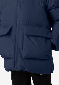 Námořnická péřová bunda s předním zipem a dvěma velkými klopovými kapsami, vyrobená z hladkého, izolačního materiálu. Texturované detaily podél švů.