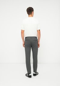 Pánské šedé tailored kalhoty s hladkou texturou, se smyčkou na opasek a dvěma zadními kapsami. Outfit je doplněn bílou košilí s texturou.