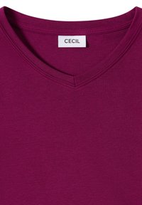 T-shirt à col en V couleur magenta foncé en coton doux, présentant une texture lisse et un design minimaliste avec une étiquette portant la mention "CECIL".