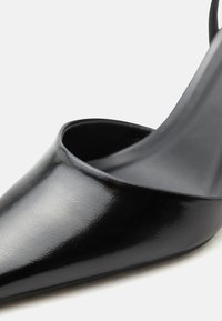 Μαύρο ψηλοτάκουνο παπούτσι με μυτερή μύτη, λεία υφή δέρματος και στενό μπροστινό άνοιγμα.