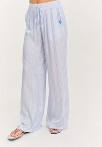 Svetlomodré nohavice s širokými nohavicami a vertikálnymi bielymi pruhmi. Obsahujú elastický pás s šnúrkou a malou modrou nášivkou na boku.