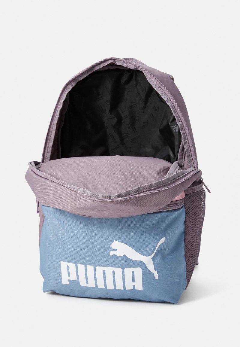 Mochila Puma en lavanda y azul. Cuenta con un bolsillo lateral de malla, cierre de cremallera, amplio interior con forro negro y logo blanco.