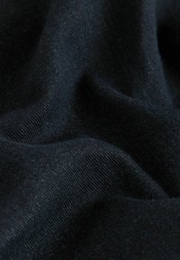 Material din bumbac negru cu o textură moale, construcție fin tricotată și un luciu subtil, evidențiind pliuri și contururi delicate.