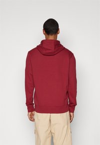 Kastanjefärgad hoodie med huva, ribbade muddar och nederkant. Tillverkad av bomullsblandat material, med en enkel och ren design.