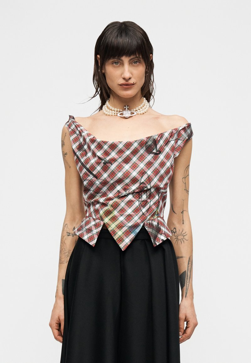 Τοπ με καρό μοτίβο σε κόκκινο, μαύρο και λευκό χρώμα με ύφασμα με υφή, σμιλεμένο σχέδιο και αιχμηρή γραμμή στο τελείωμα· φορεμένο με μαύρη φούστα.