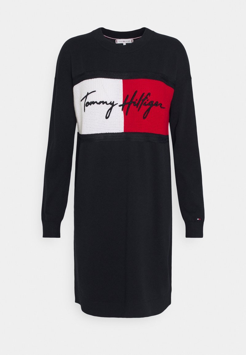 Robe noire à manches longues avec un panneau tricoté blanc et rouge sur la poitrine, avec le logo manuscrit "Tommy Hilfiger" en noir.