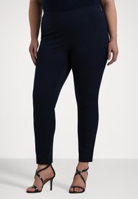 Mörkblå skräddarsydda byxor i stretchmaterial, med slim fit och ankellängd. Bärs med svarta sandaler med hög klack och remmar.