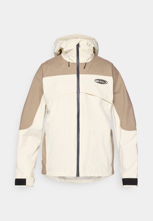 Giacca a vento beige e marrone chiaro con zip frontale completa e polsini regolabili in Velcro, caratterizzata da un piccolo logo nero sul petto.