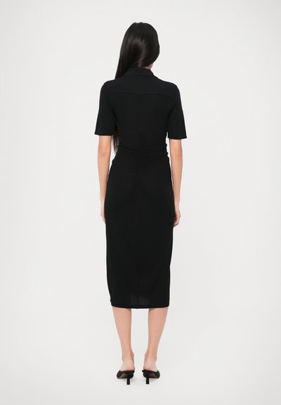 Crna midi haljina s kratkim rukavima, uskim krojem i naboranim detaljima na stražnjoj strani, izrađena od glatkog materijala s ravnim rubom.