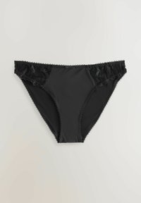 Czarne majtki w stylu bikini z koronkowymi zdobieniami po bokach i małą kokardką na środku na jednolitym jasnym tle.