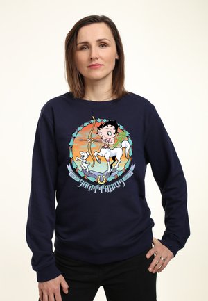 Marineblå sweatshirt med et farverigt tegneserieprint af en pige med en sløjfe og en hest, omgivet af et cirkulært design, med en blød tekstur.