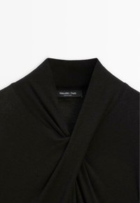 Černý top s výstřihem do V a detailním zavěšením. Vyroben z hladkého materiálu, obsahuje štítek s značkovým nápisem "Massimo Dutti".