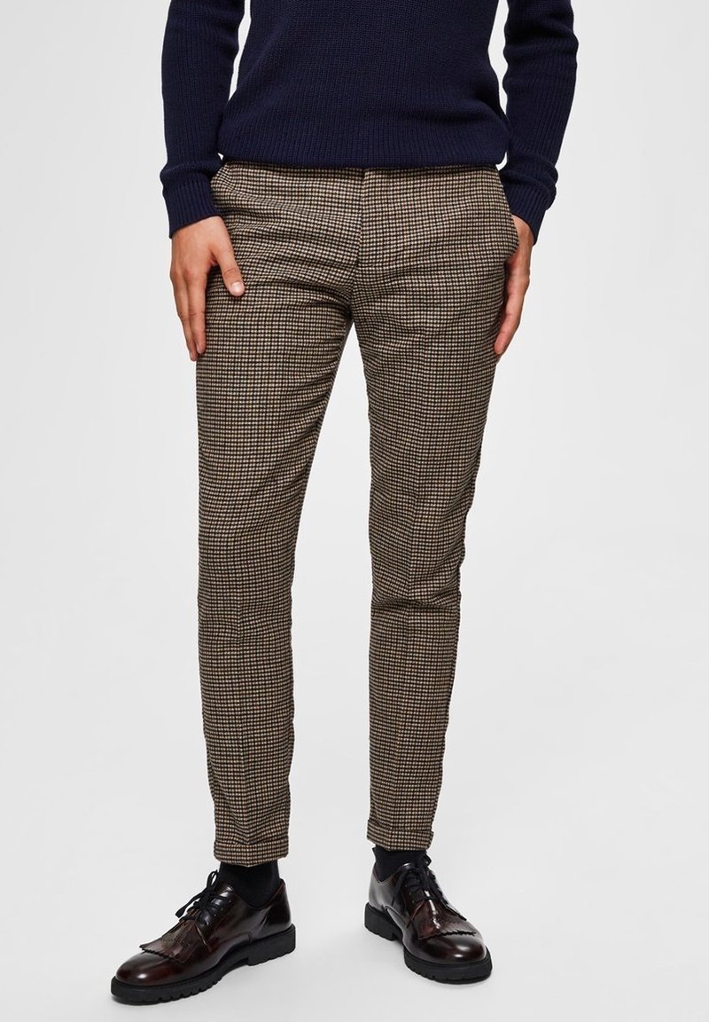 Rutiga bruna byxor med slim fit, med subtil textur. Parat med glänsande svarta snörskor, vilket fulländar en skräddarsydd look.