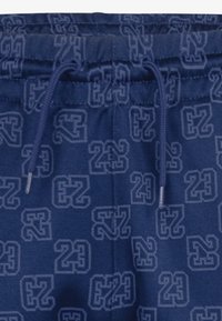 Marineblå shorts med elastisk talje og snørre. Har et gentaget mønster af tallet "23" i en mørkere nuance. Glat tekstur.