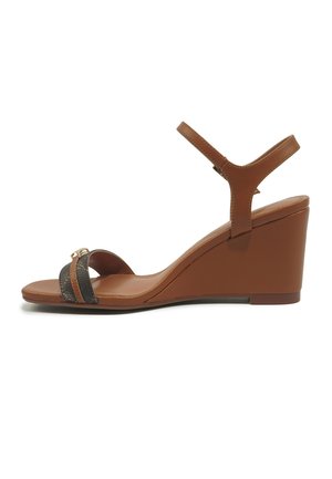 Bruine sleehak sandaal met enkelriem, een zwarte en gouden decoratieve voorriem en een hak van gemiddelde hoogte.