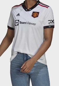 Camisa blanca del Manchester United con mangas cortas, cuello negro, acentos rojos y logotipos de TeamViewer y DXC Technology.