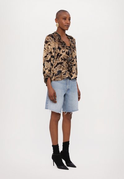 Black and gold paisley blouse with ruffle detail, paired with light blue denim shorts. Model wears black ankle boots and black socks.