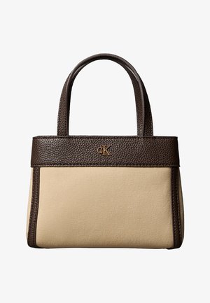 Bolso de mano de lona beige con detalles y asas de piel marrón oscuro, con un pequeño logo dorado "cK" en el frente.