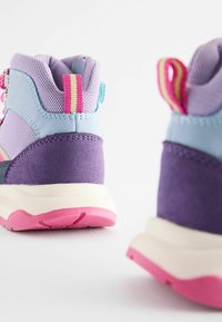 Baskets de sport violet et bleu clair en matériaux maillés et en daim ; caractéristiques des accents roses, une semelle texturée et une sangle de traction pour un enfilage facile.