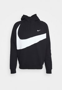 Svart hoodie med en vit Nike swoosh-grafik och zippered hals. Har ribbade manschetter och fåll, tillverkad av mjukt tyg för komfort.