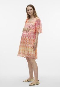 Oblačilo za nosečnice iz lahkega, mehko padajočega materiala z barvitim prelivanjem roza in oranžne barve ter subtilnim tie-dye vzorcem in kratkimi rokavi.