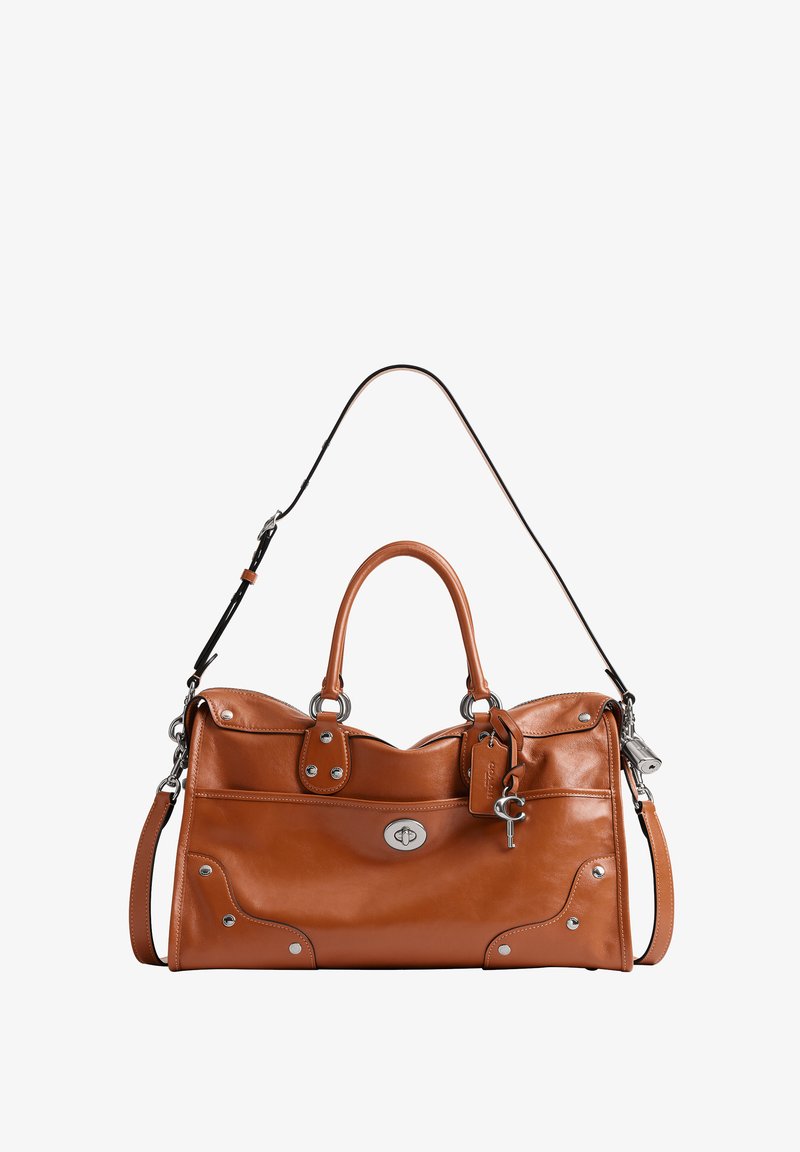 Sac à main en cuir marron avec garnitures argentées, poignées supérieures, bandoulière amovible, poche avant et porte-clés attaché à une étiquette.