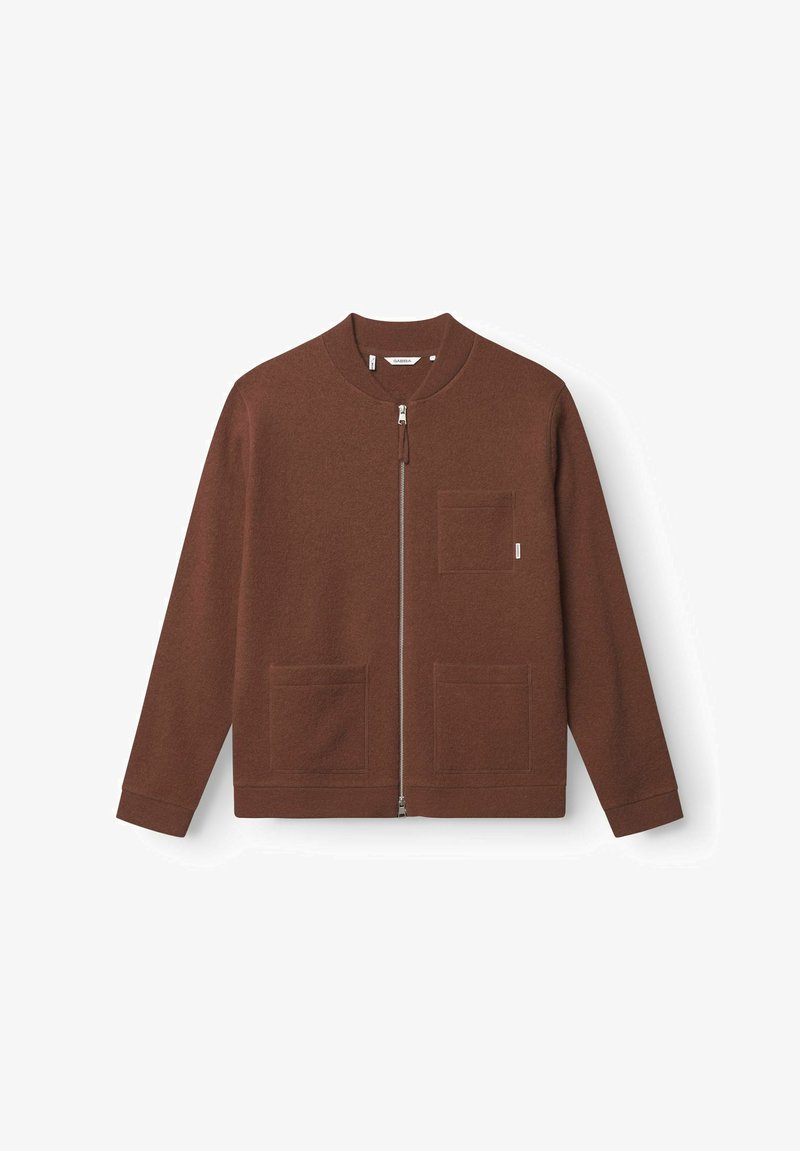 Veste en polaire marron avec un col rond, fermeture éclair sur le devant et deux poches à rabat. Elle présente une texture douce et un design décontracté.