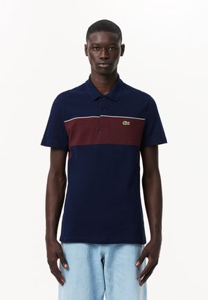 Dunkelblaues Poloshirt mit einem burgunderfarbenen Streifen und weißen Akzenten. Hergestellt aus strukturiertem Baumwollmaterial, mit einem Kragen mit zwei Knöpfen und grünem Logo.