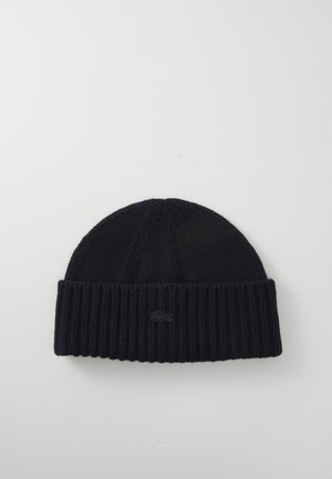 Navy knitted beanie with a ribbed texture, featuring a folded cuff and a small embroidered logo on the front.