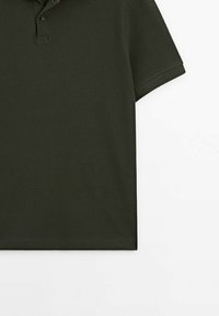 Polo vert foncé à manches courtes avec texture côtelée, patte de boutonnage à deux boutons et poignets pliés, posé à plat sur fond blanc.