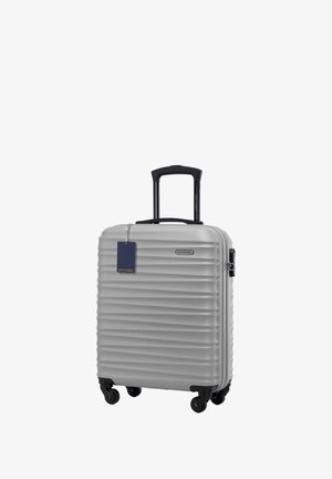 Stříbrný tvrdý kufr s vertikálním žebrovaným vzorem, dvěma koly, teleskopickou rukojetí a připojenou modrou cedulkou. Značka: WITTCHEN.