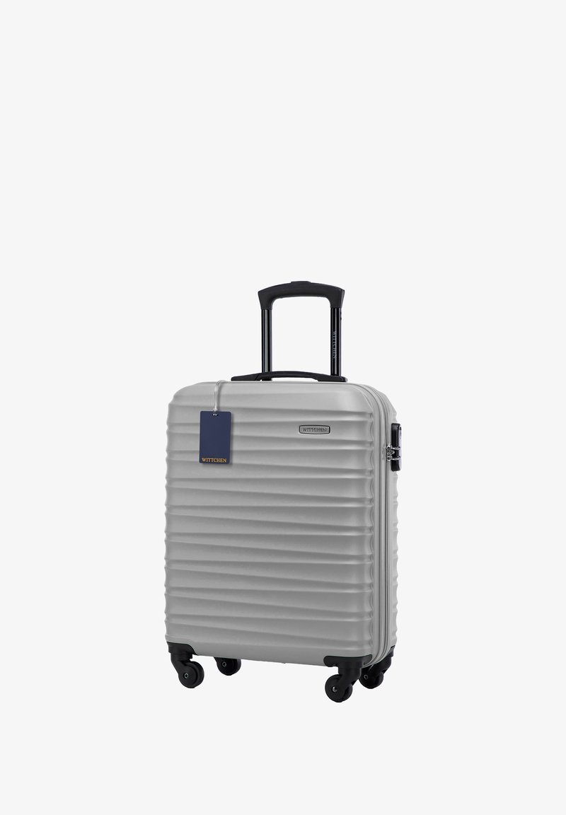 Zilveren harde koffer met verticale ribbelstructuur, twee wielen, telescoop handvat en een blauwe tag bevestigd. Merk: WITTCHEN.