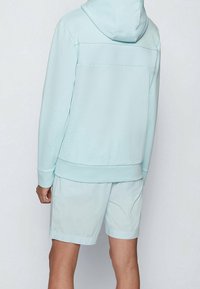 Sudadera azul claro con un panel texturizado en la parte trasera, combinada con pantalones cortos azul claro a juego. Tejido suave, corte relajado y diseño con capucha.