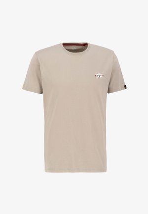 Beige színű pamut póló rövid ujjakkal, kerek nyakkivágással, és egy kis piros-fehér logóval a bal mellen. Sima textúra, laza dizájn.