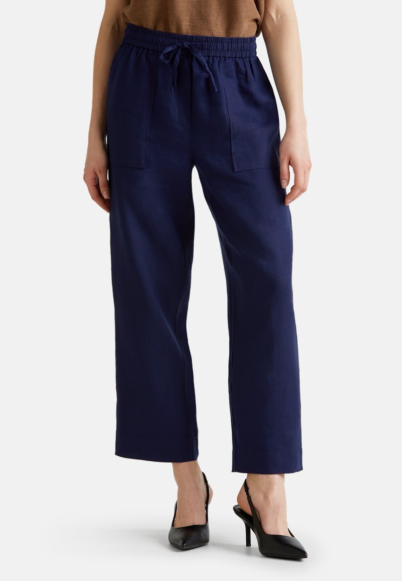 Pantalones de lino azul marino con cintura elástica, detalle de cordón y dos bolsillos frontales, presentando un diseño relajado y de pierna ancha.