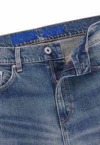 Blå denimjeans med en urtvättad finish, med en silverfärgad dragkedja, knappstängning och en sydd etikett med texten "HUGO LASH."