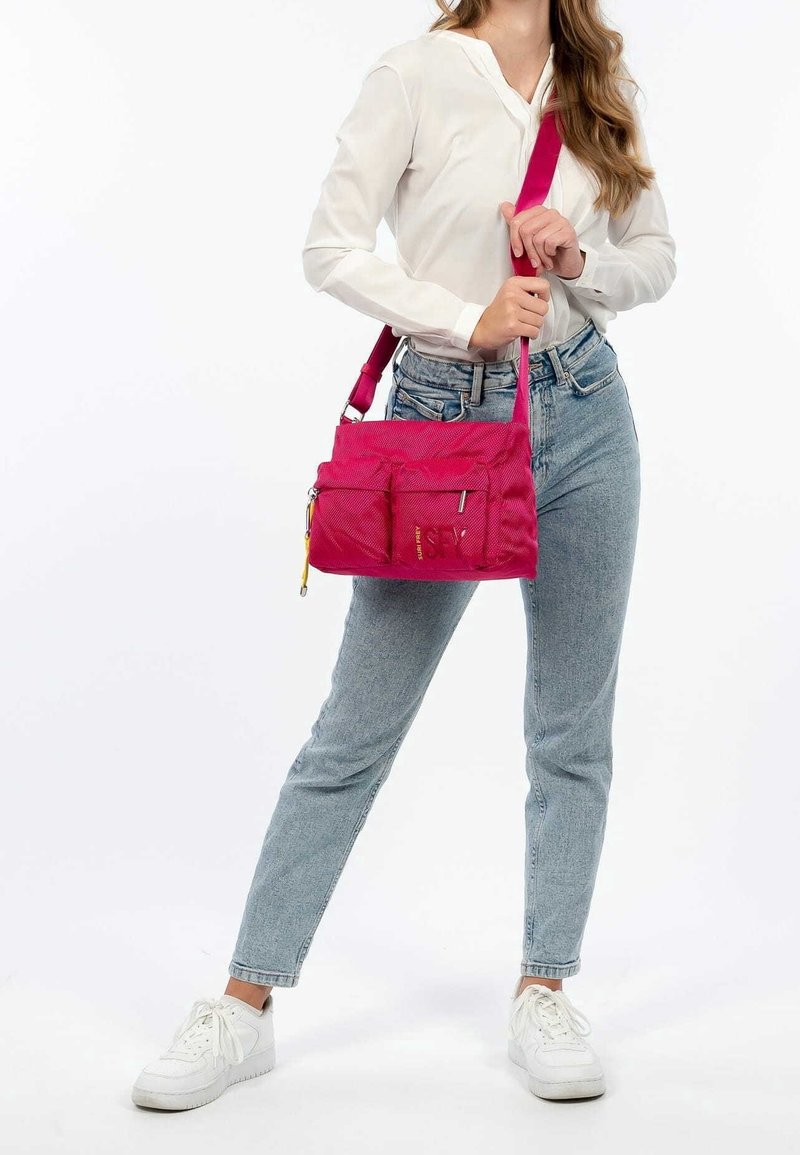 Sac à main en nylon rose avec plusieurs poches avant, une bandoulière et une fermeture éclair. Texture lisse et forme rectangulaire.