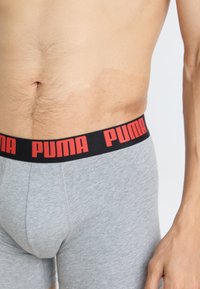 Szürke boxer alsónadrág fekete derékrésszel, amelyen piros "PUMA" felirat található. Az anyag sima tapintású, és testhezálló fazonú.