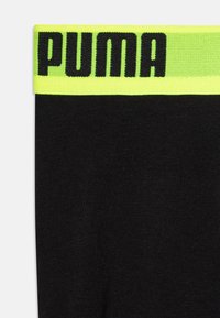 Črne bombažne bokserice s širokim fluorescenčno zelenim pasom, na katerem je črno blagovna znamka "PUMA". Mehka tekstura in elastičen material.
