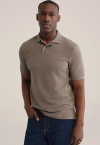 Korte mouwen, poloshirt met kraag in beige katoen met een slanke pasvorm. Heeft een knoopsluiting en een klein zwart logo op de linkerborst.