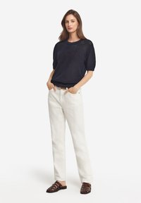 Marinfläder t-shirt med kort ärm och strukturerad mönster, kombinerad med vita linbyxor och bruna remsandaler. Enkel, avslappnad passform.